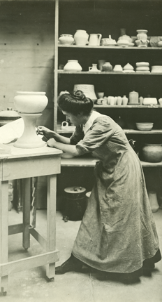 A woman in the 1900s working on pottery in a class